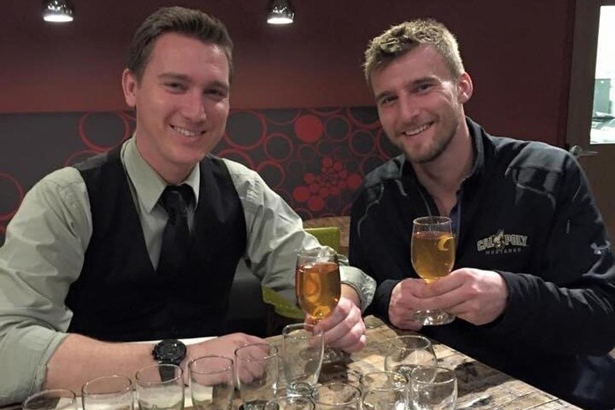 two men sitting at a table with glasses of beer