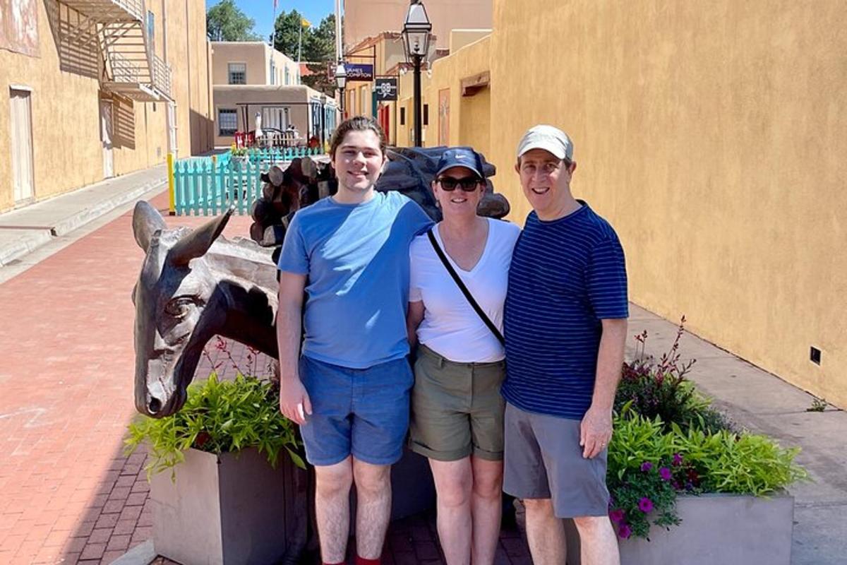 three people standing in front of a statue of a giraffe