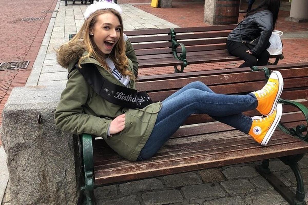 a young woman sitting on a bench with her mouth