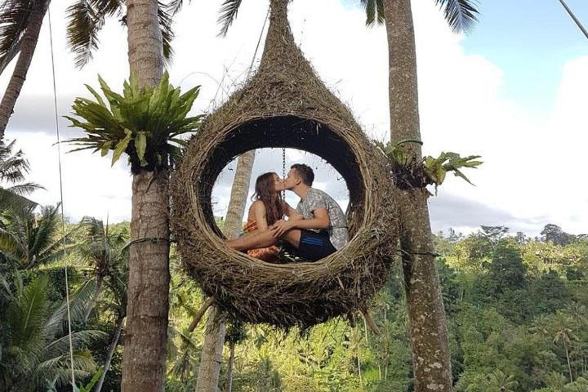 un uomo e una donna seduti in un nido appeso a un albero