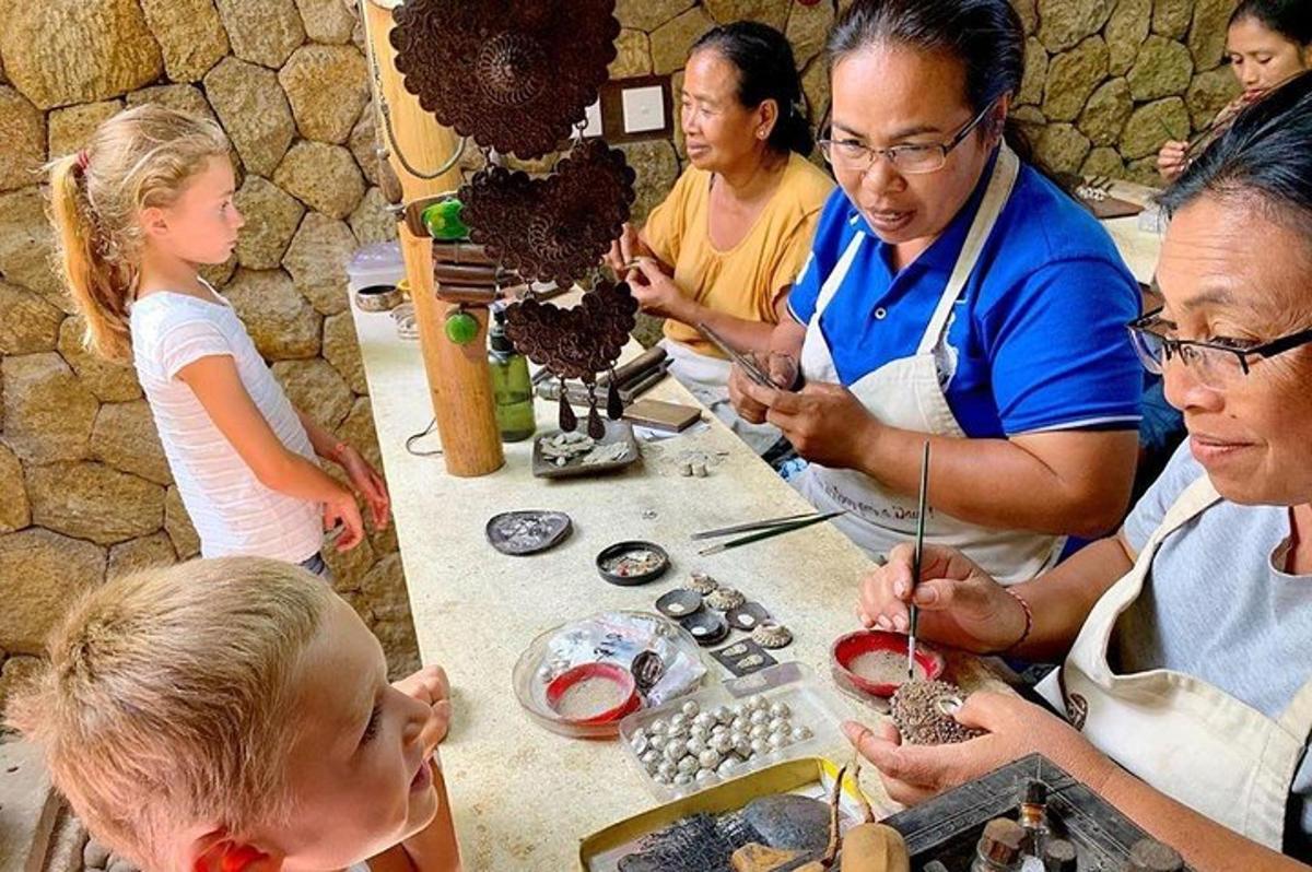a group of people standing around a table making beads