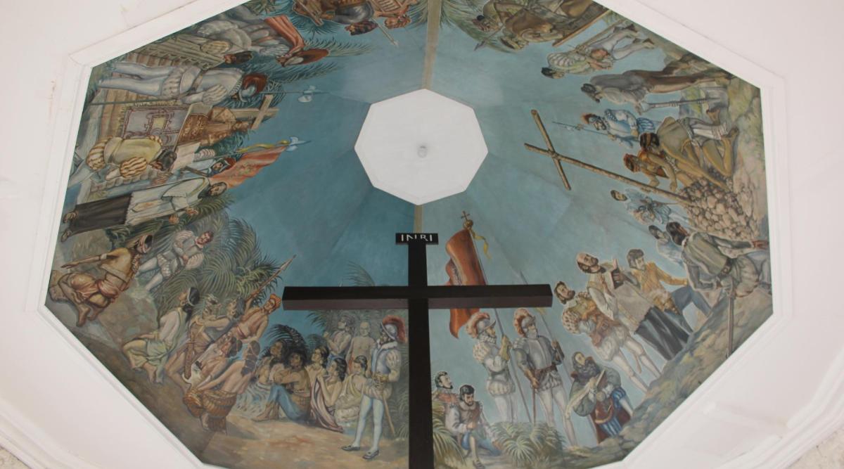 a cross on top of a wall with a painting