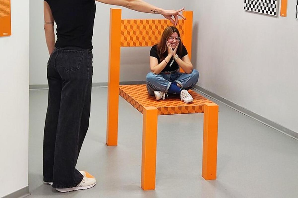 a woman sitting on a orange chair while a person is standing