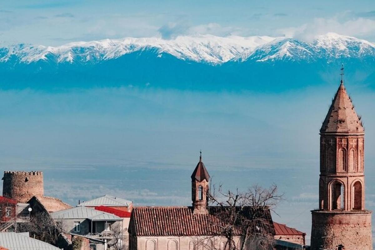 un oraș cu un turn cu ceas și un munte înzăpezit