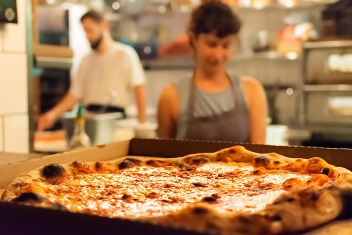 una persona en una cocina con una pizza en una caja