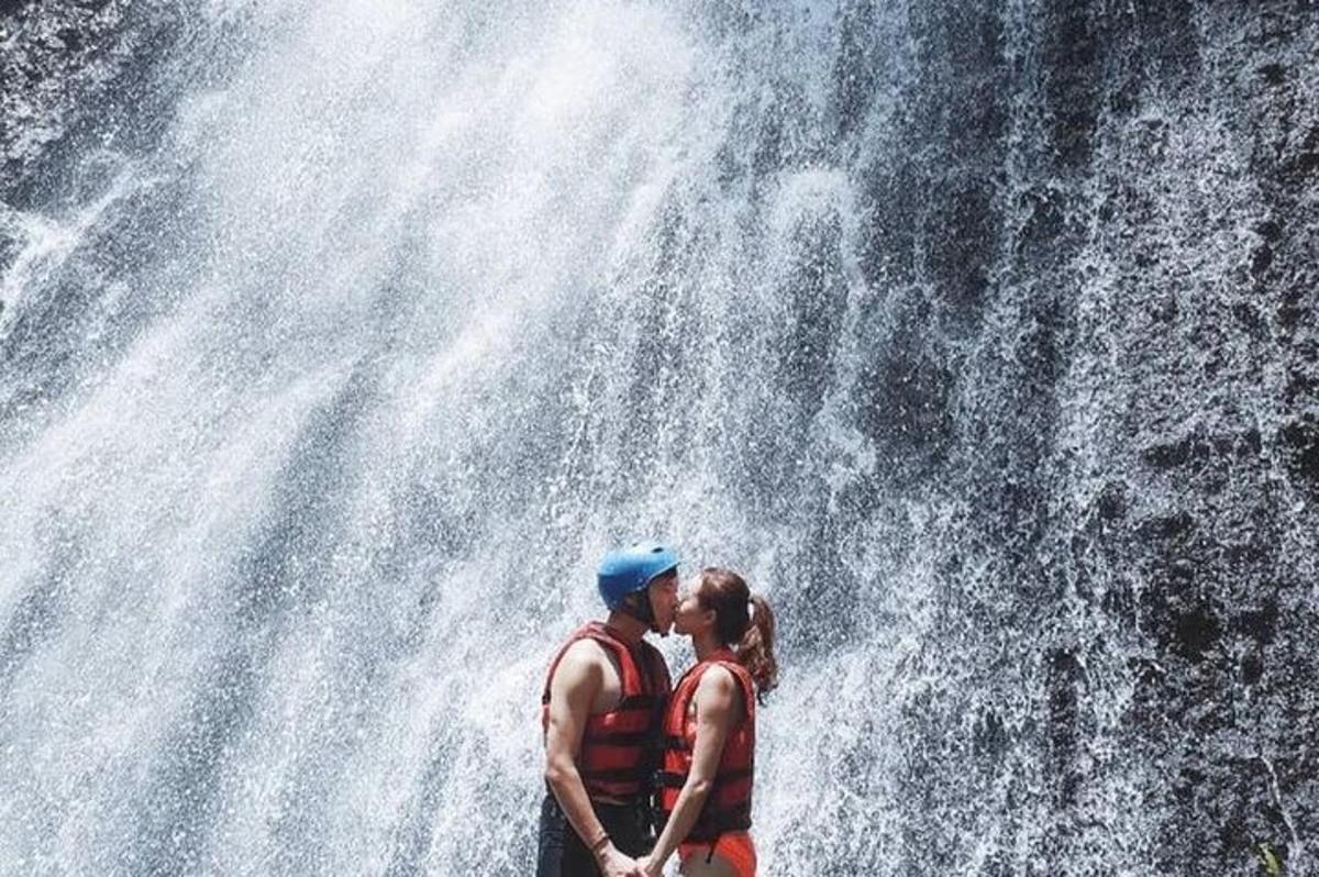 a man and woman standing in front of a waterfall