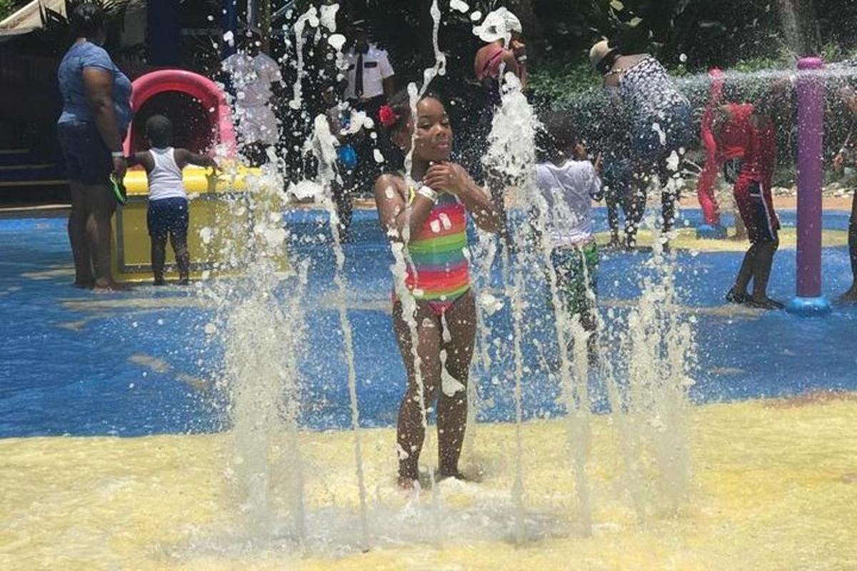 uma menina brincando em uma fonte em um parque aquático