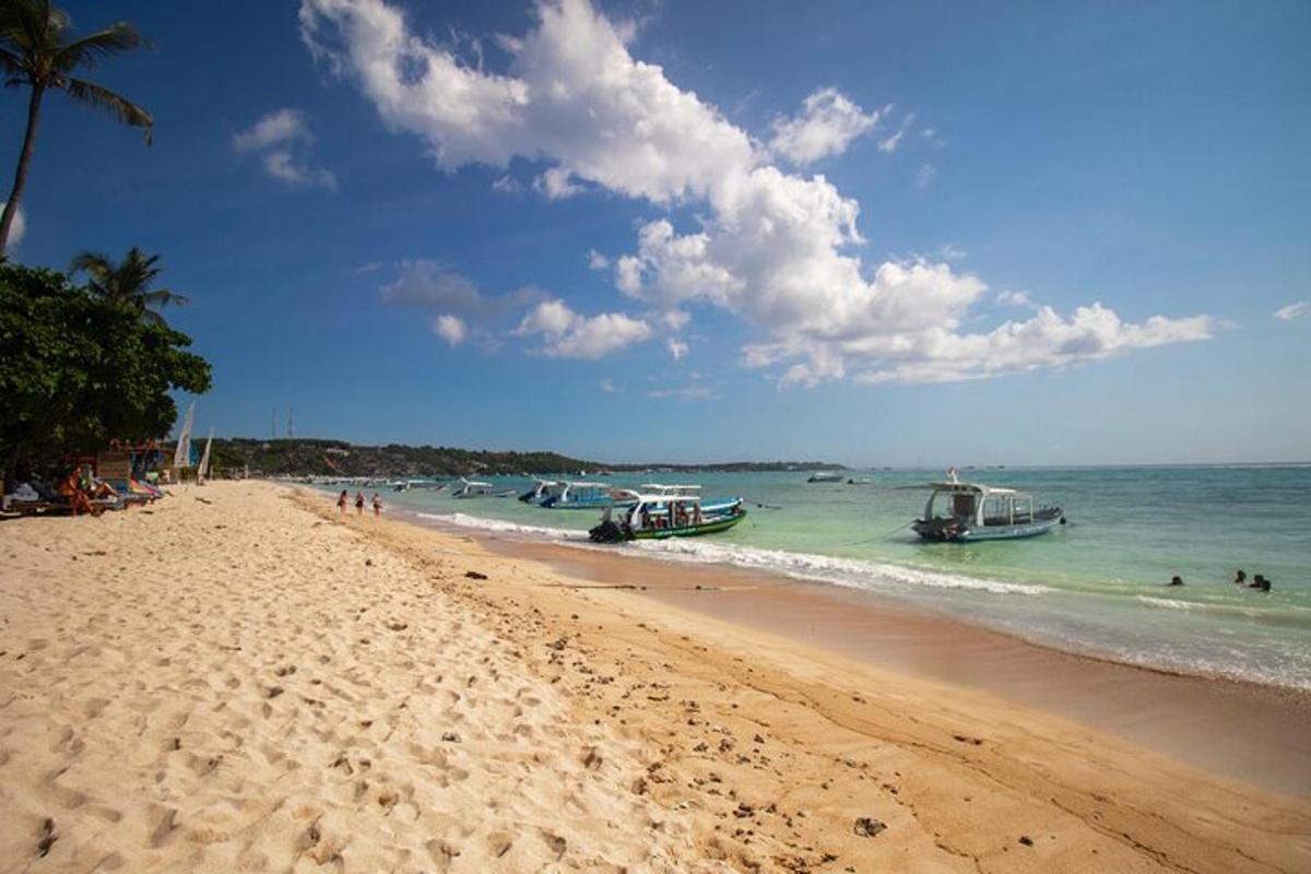 ein Strand mit Booten im Meer und Menschen im Wasser