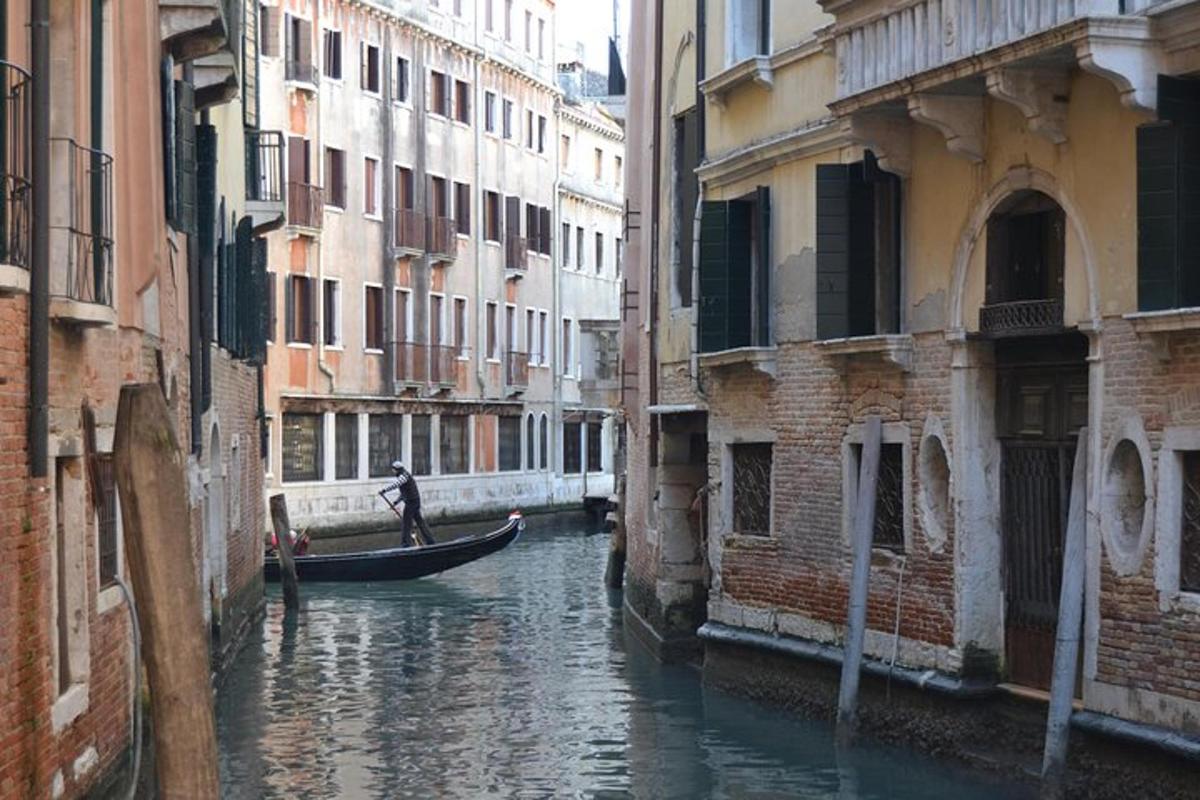 un uomo su una barca in un canale tra gli edifici
