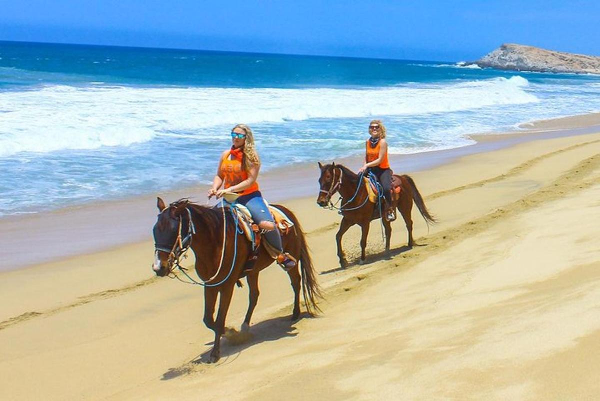 duas mulheres estão cavalgando na praia