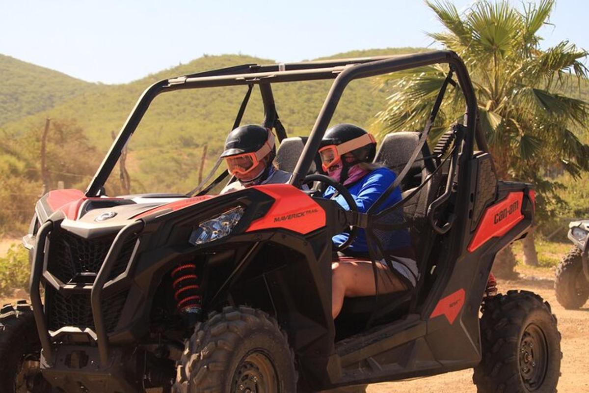 dvoje ljudi se voze u ATV-u po zemljanom putu