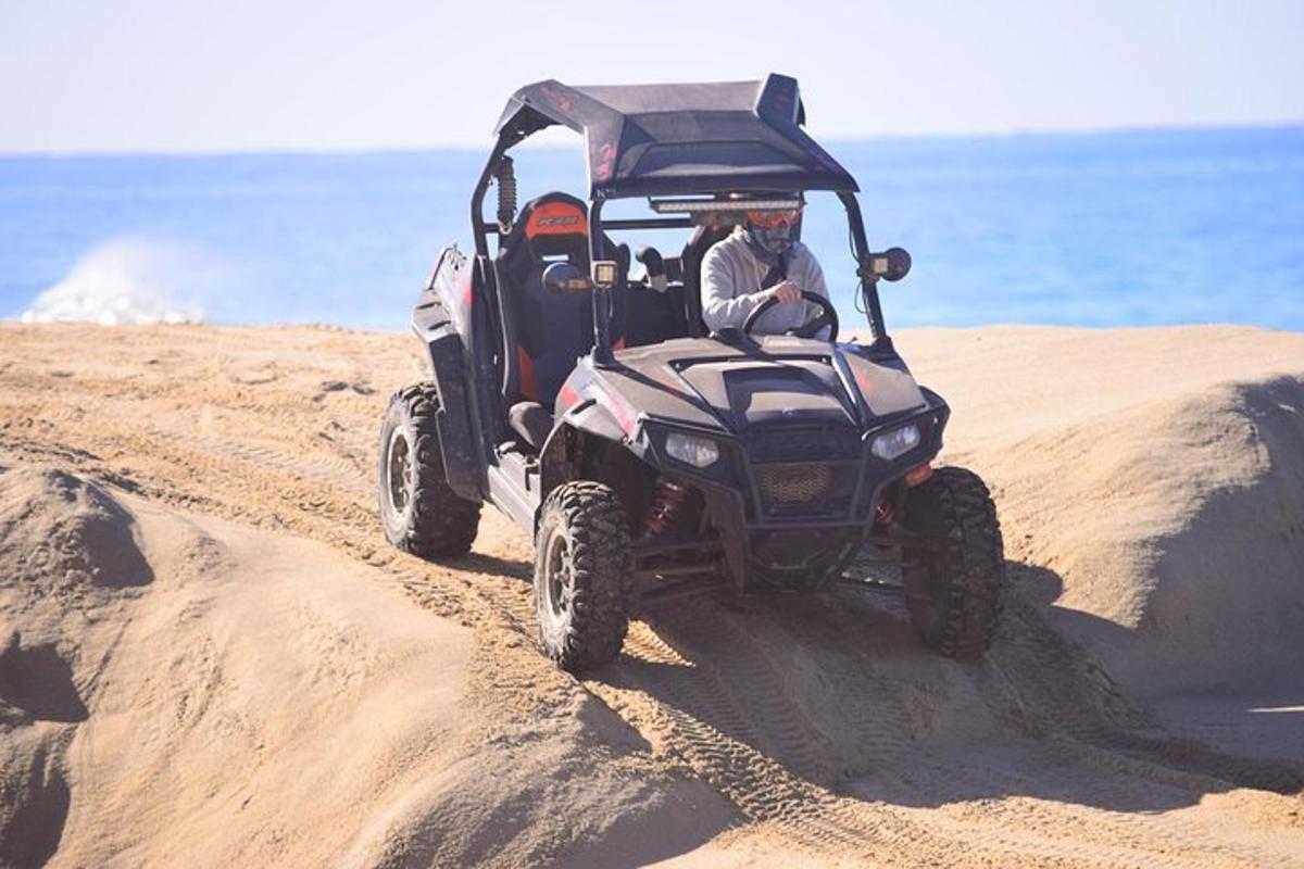 een man die met een ATV op het strand rijdt