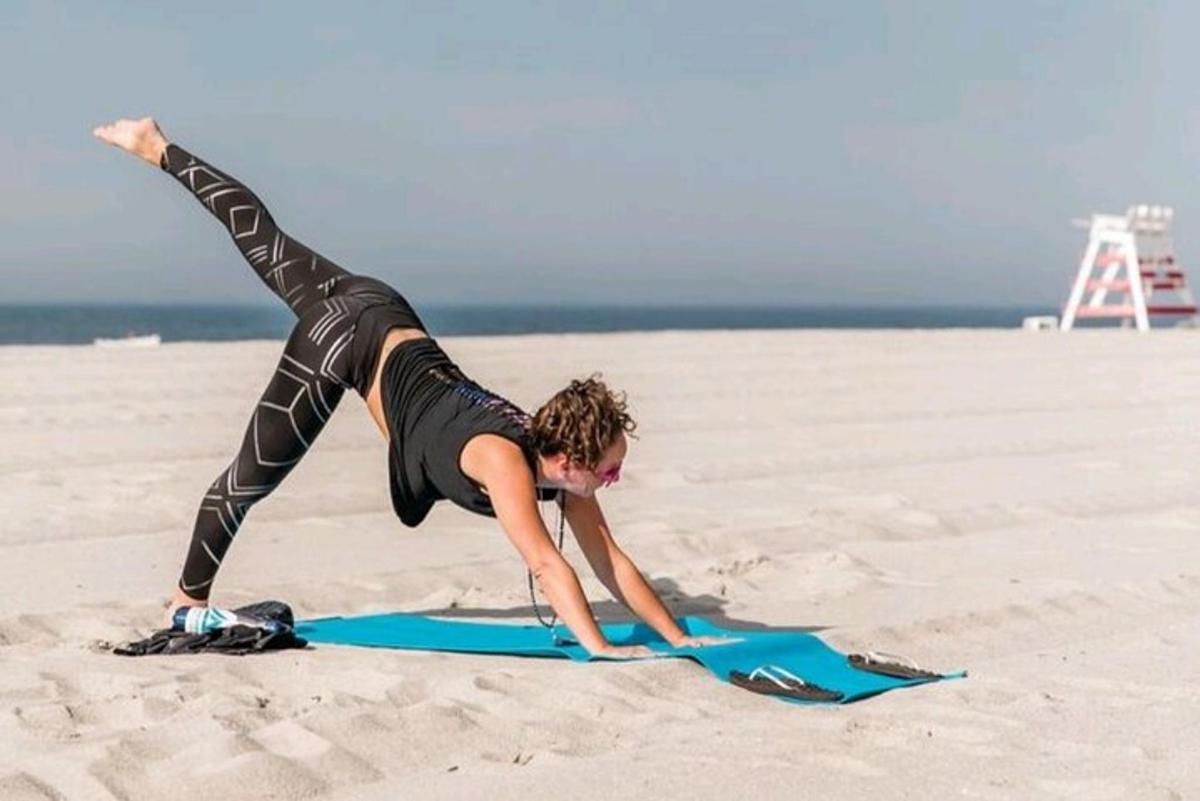 a woman doing a handstand on a surfboard on the beach