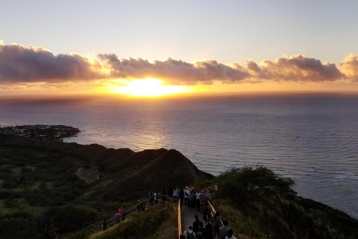 a group of people standing on a hill watching the sunset