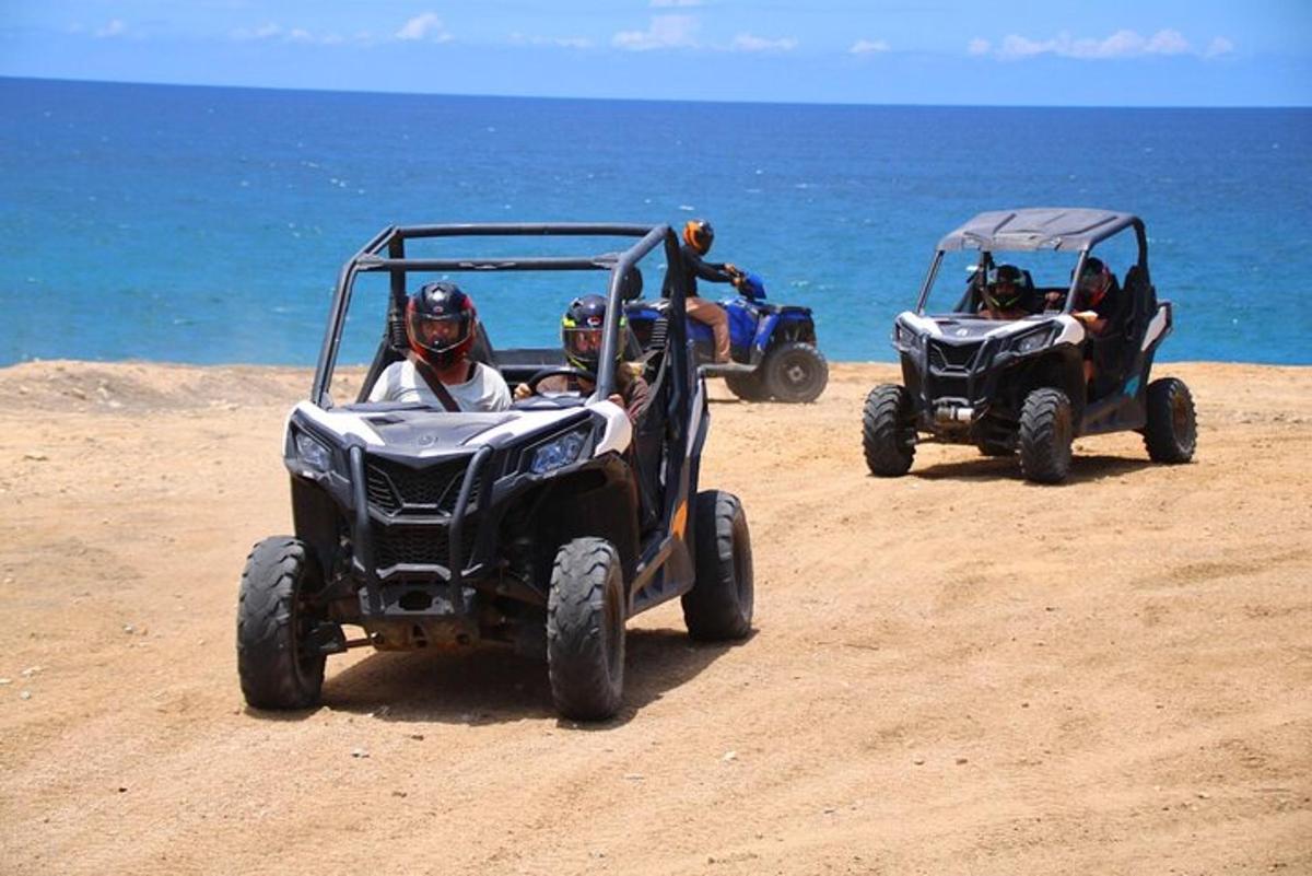 dues persones conduint quads a la platja