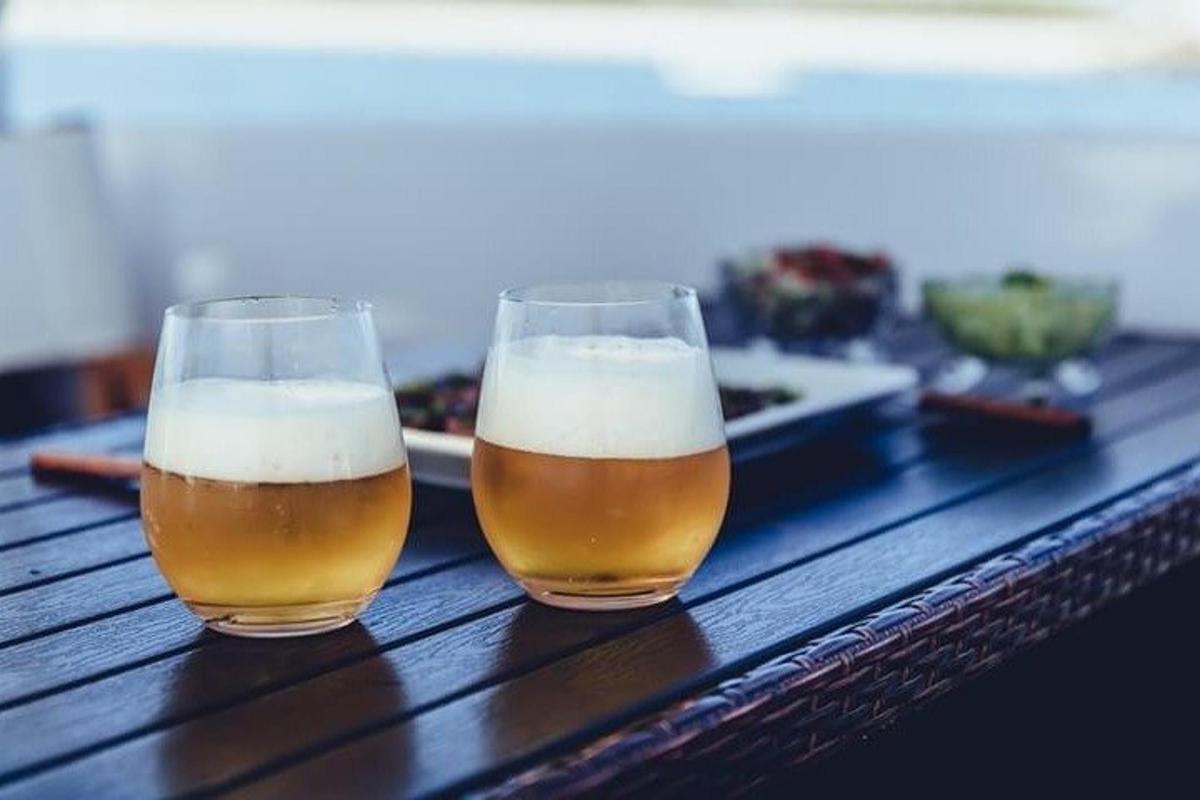 Dos vasos de cerveza sobre una mesa de madera.