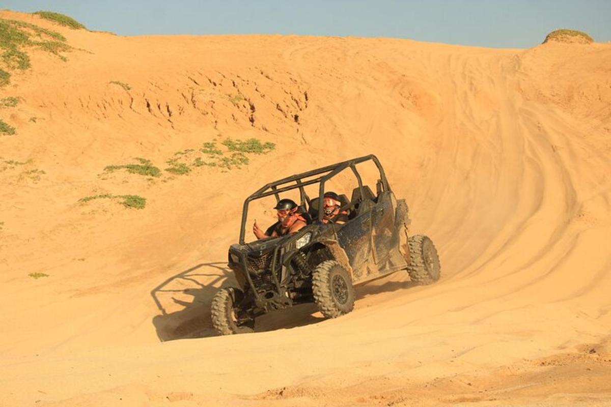 three people in a jeep in the desert