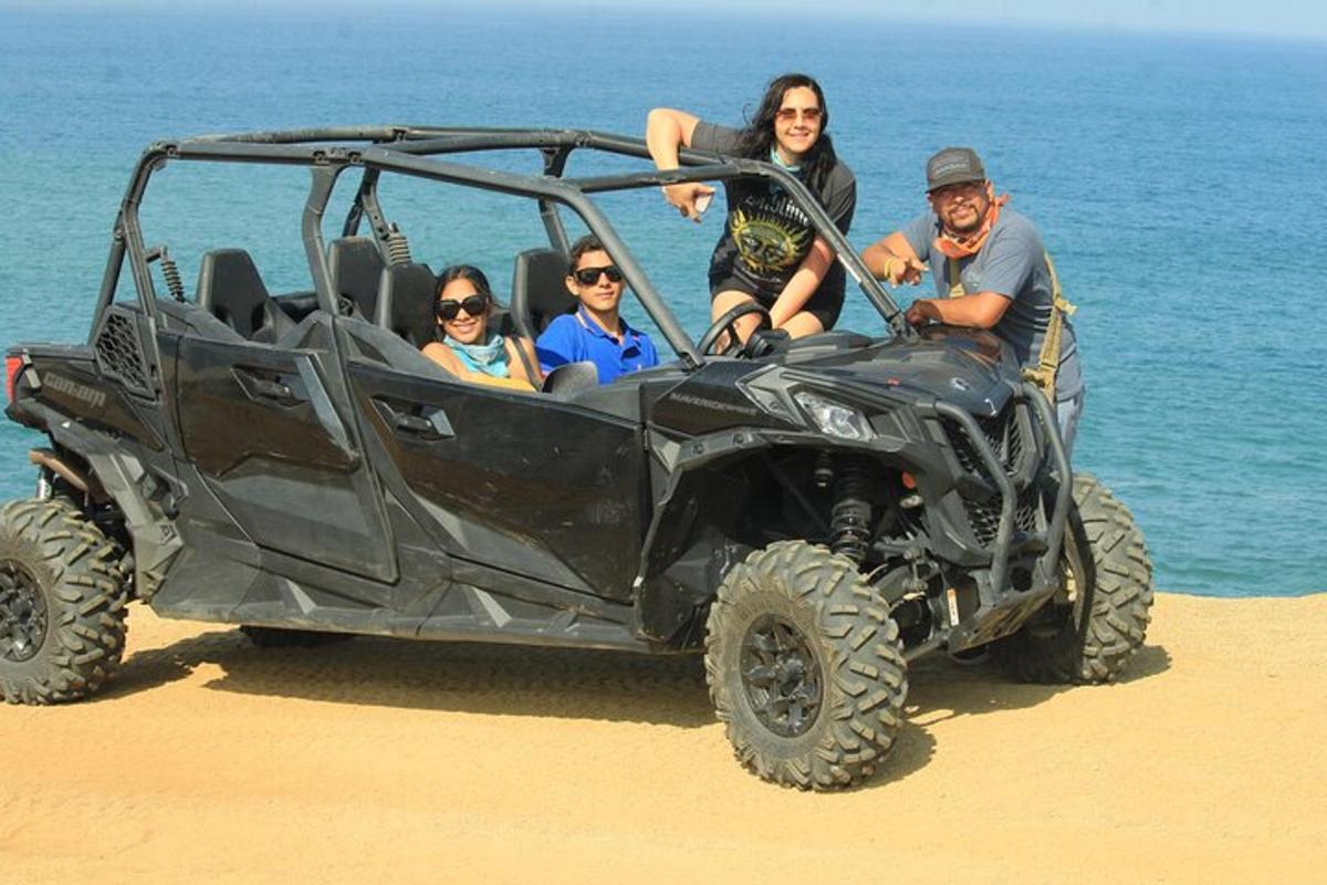 a group of people sitting in a black jeep on the beach