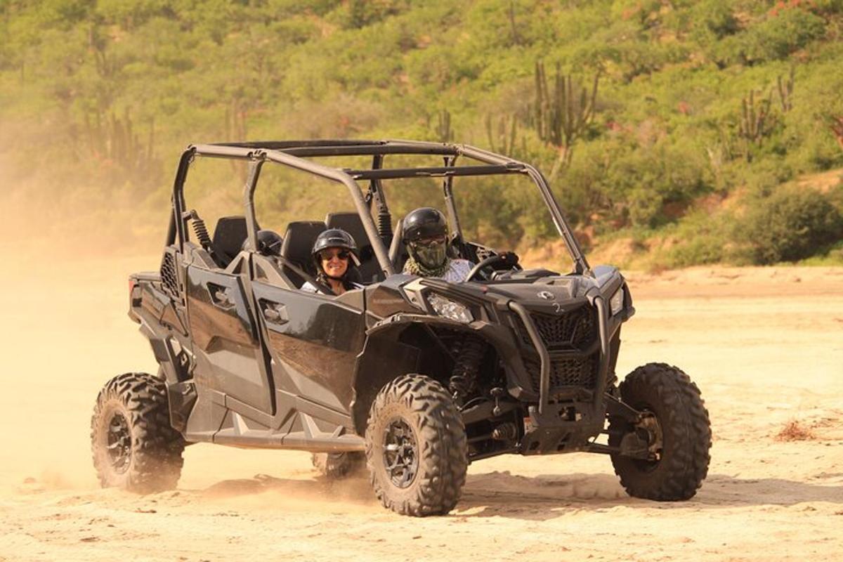 two people riding in an atv on a dirt road