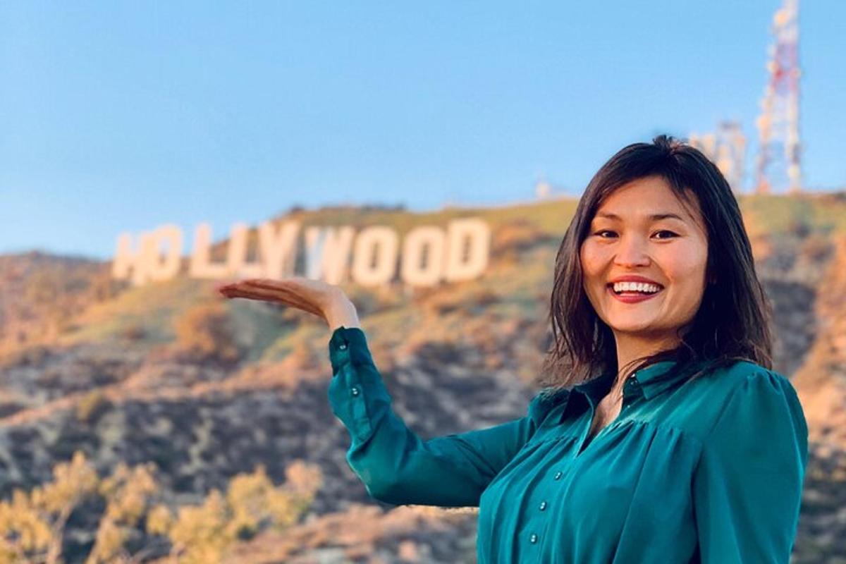 ženska stoji pred hollywoodskim znakom