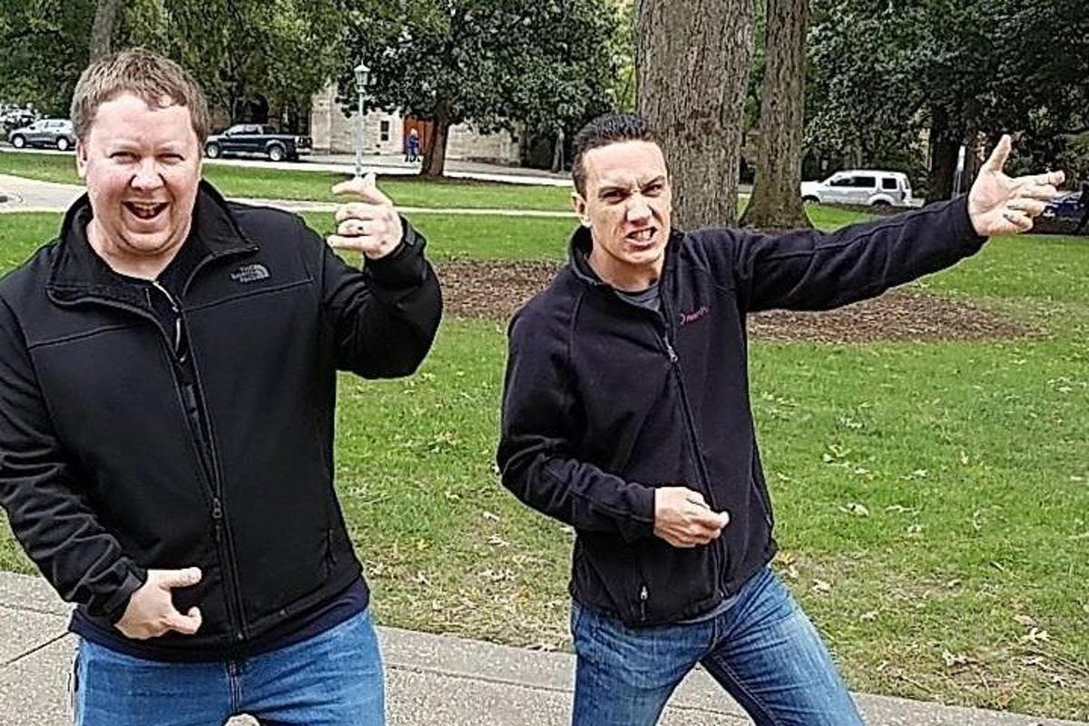 two men standing in a park with their hands up