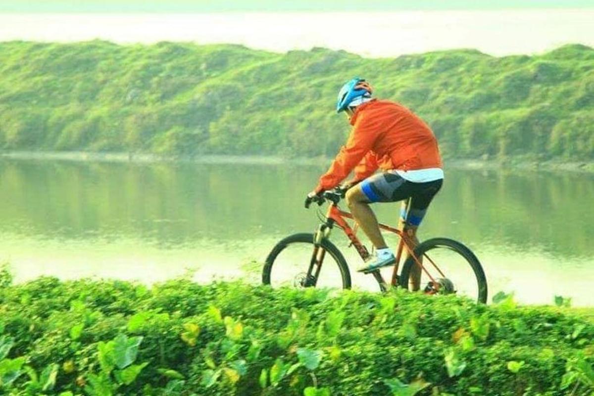 a man riding a bike on a hill next to a lake