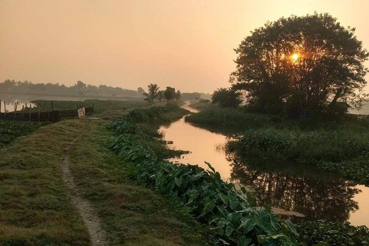 a dirt road next to a river at sunset