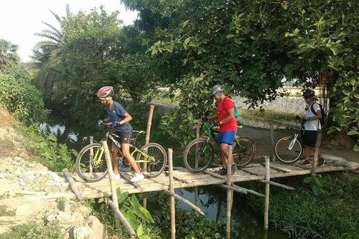 three people standing on a bridge with their bikes