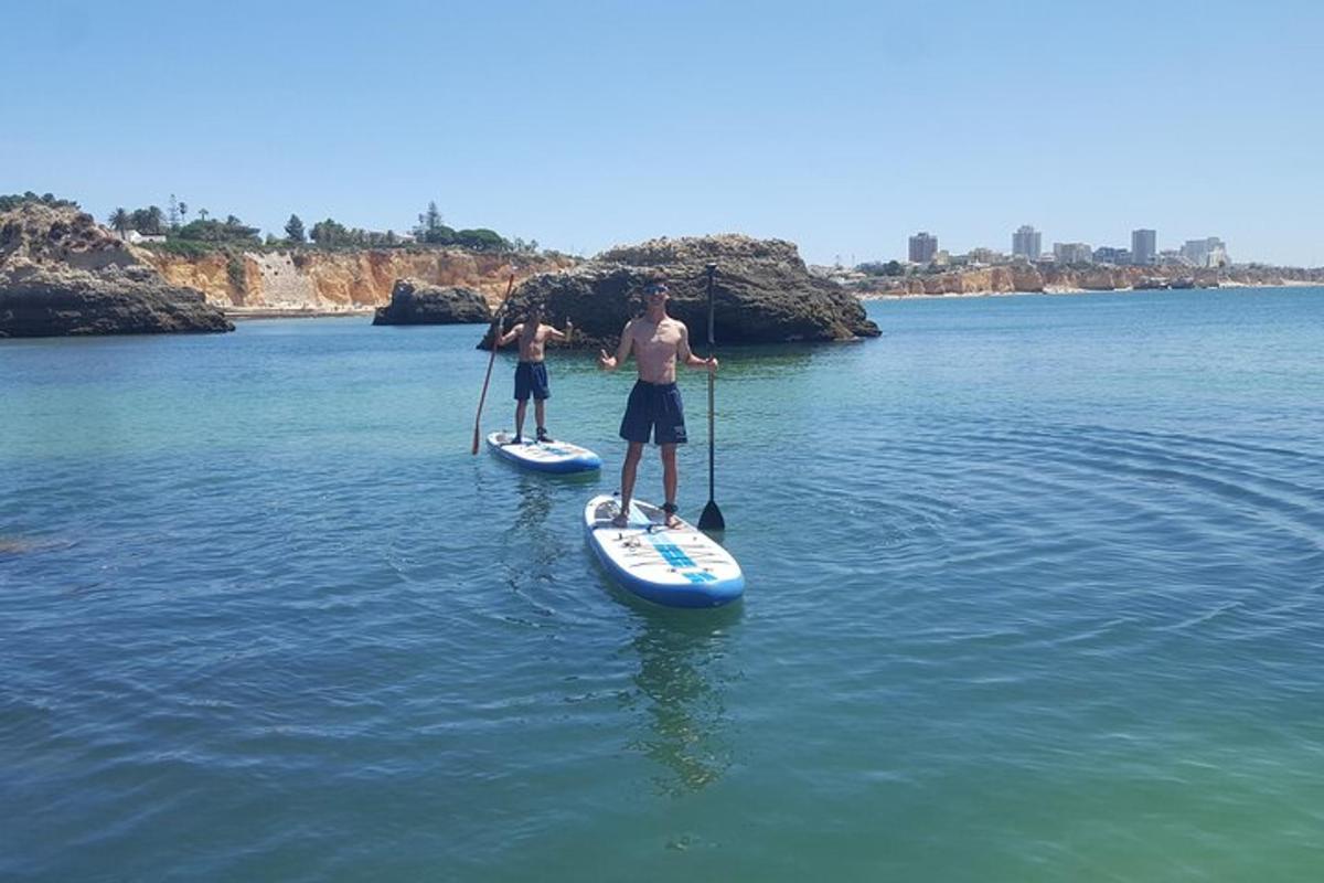 dos homes estan drets sobre taules de paddle surf a l'aigua