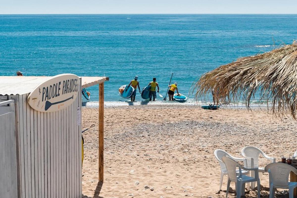 un grup de persones caminant per la platja amb taules de surf