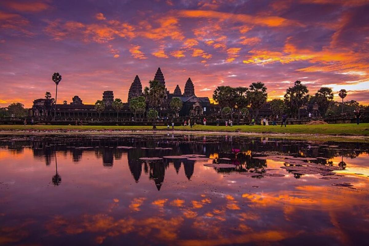 a sunset over a pond in front of a temple