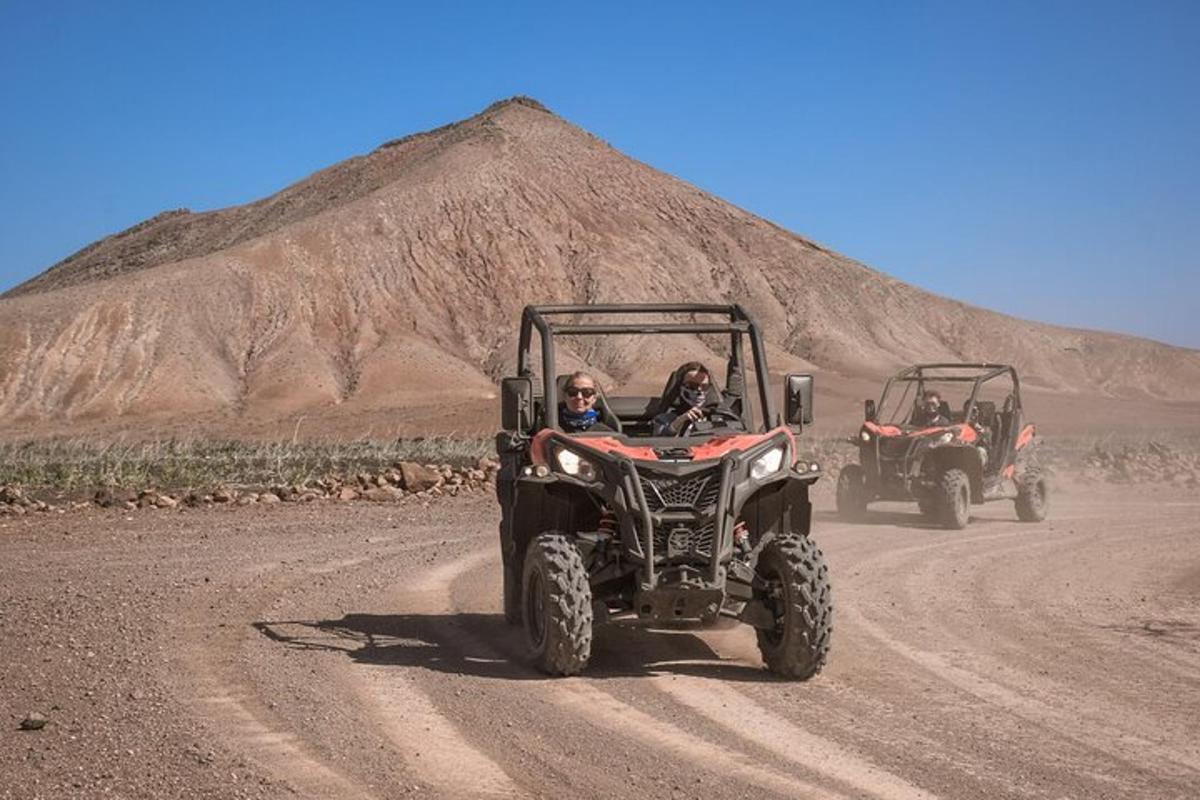 two people in atvs driving down a dirt road