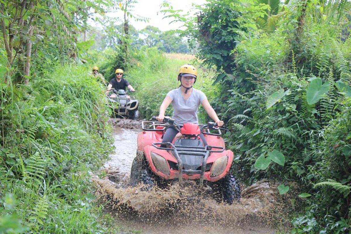 a woman riding a four wheeler through a muddy trail