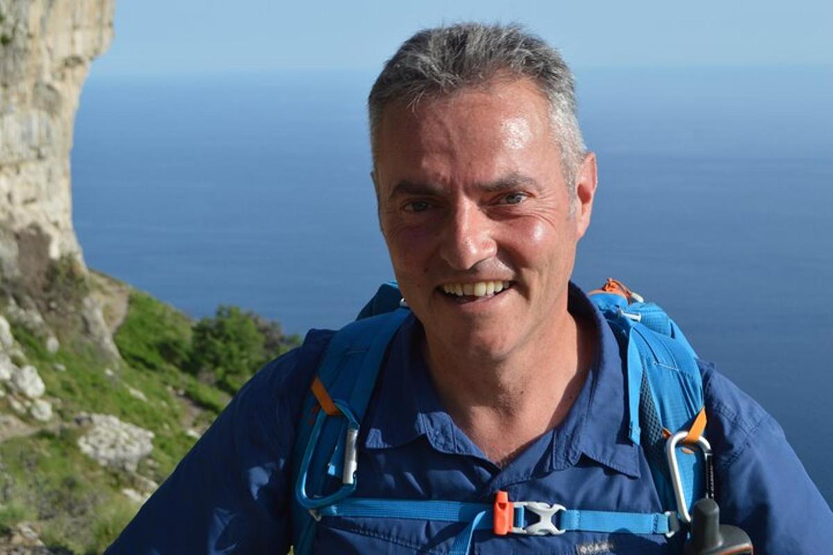 Un hombre con una chaqueta azul sonriendo a la cámara.