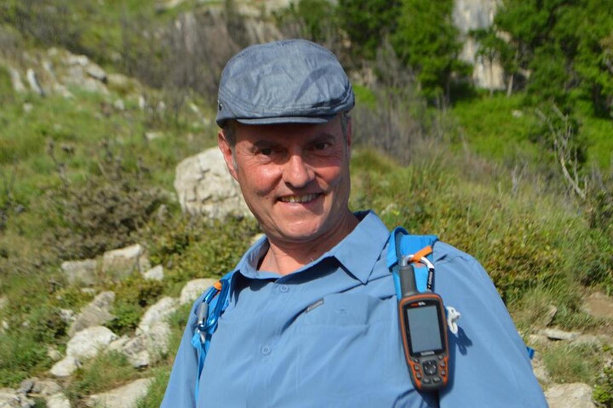 Un hombre que lleva un sombrero y un teléfono celular alrededor del cuello.