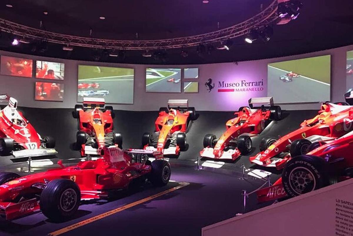 a room with three red racing cars on display
