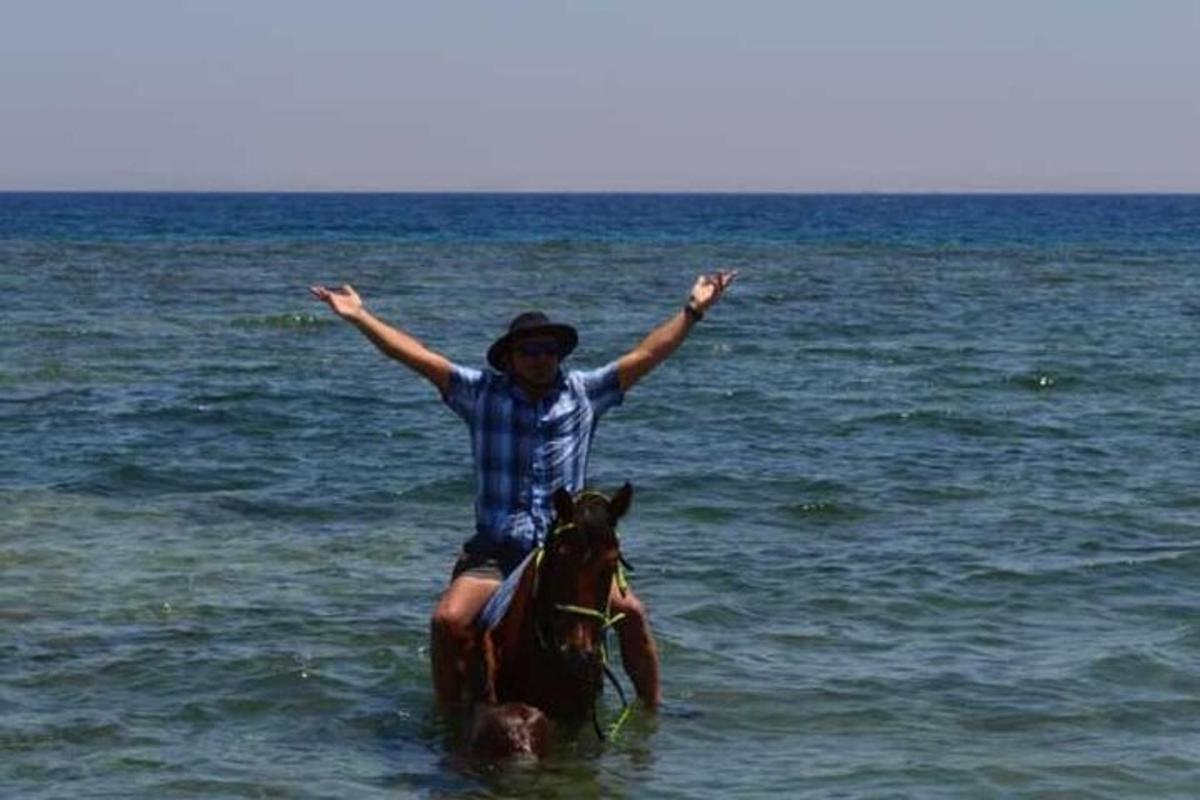 Un hombre está montando a caballo en el agua.