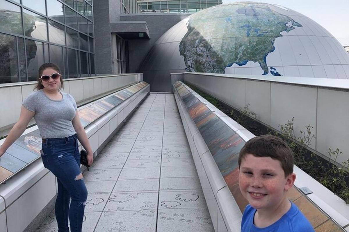a woman and a boy standing on a walkway in front of a globe