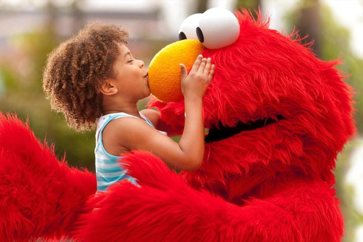a young girl is kissing a red bird with an orange
