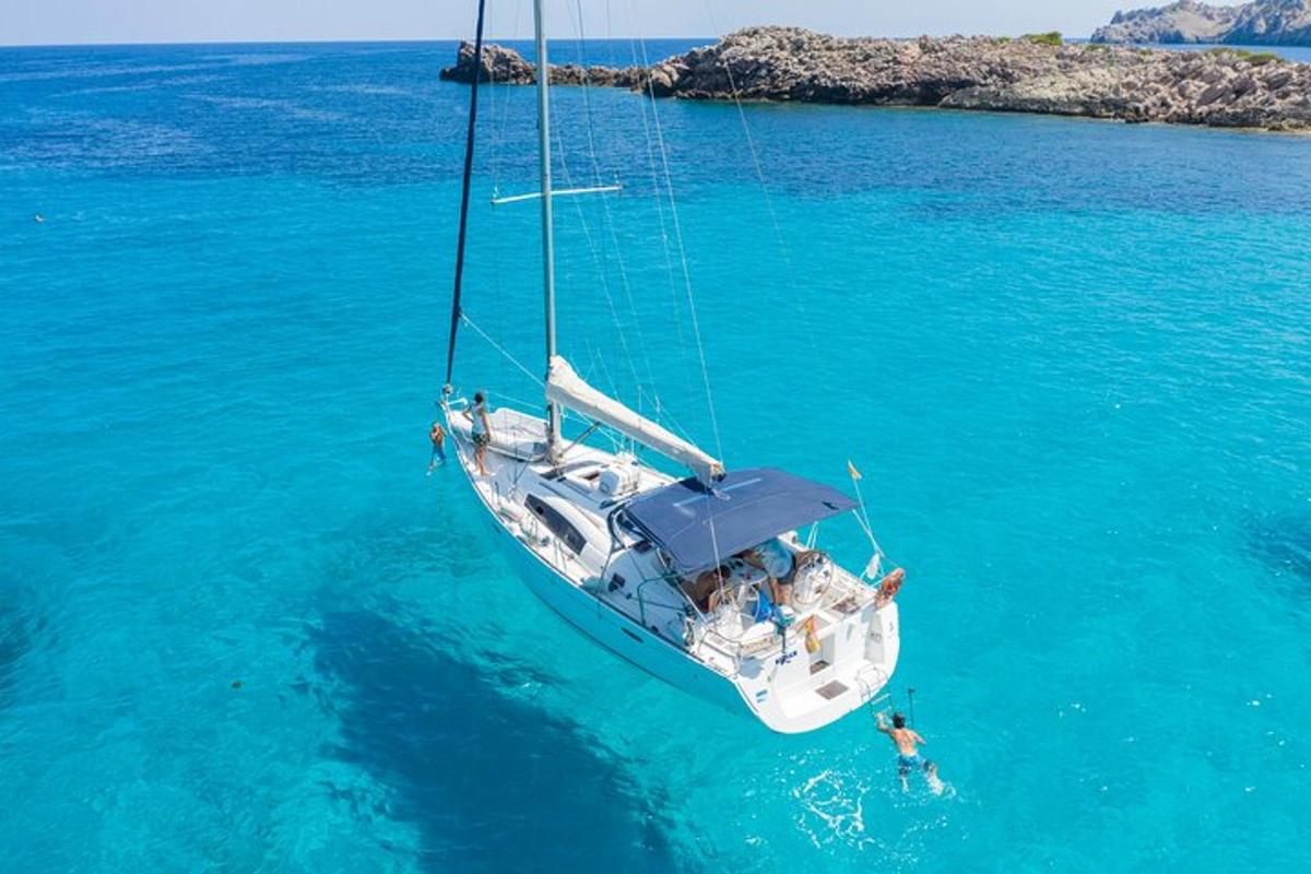 ένας άντρας κολυμπάει στον ωκεανό δίπλα σε ένα ιστιοφόρο