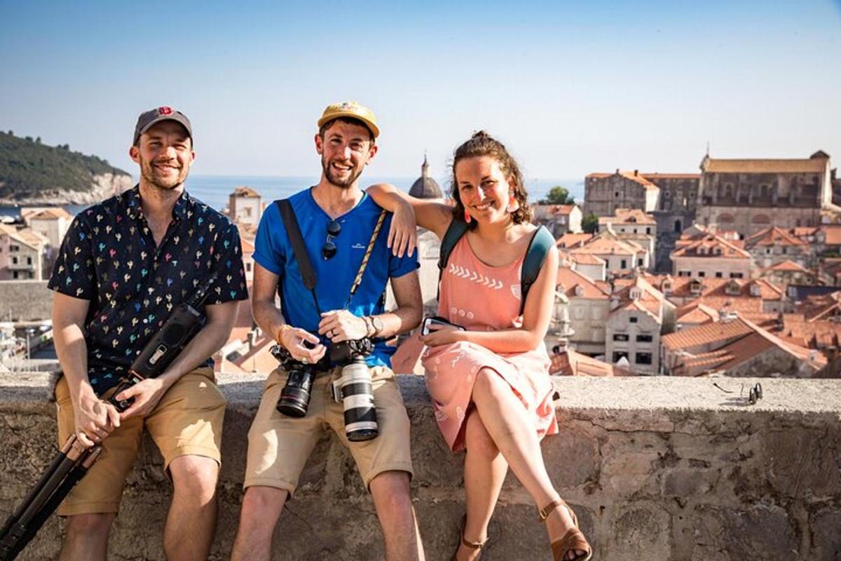 um grupo de três pessoas sentadas em um muro com câmeras