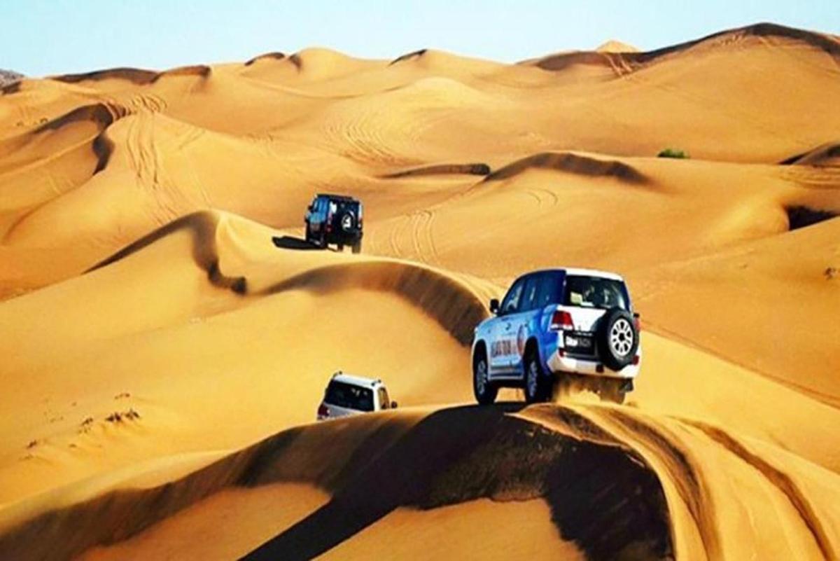 tre camion che guidano sulle dune di sabbia nel deserto