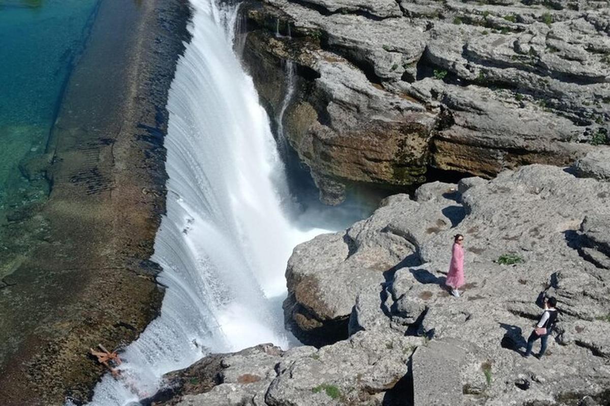 due persone in piedi sulle rocce accanto a una cascata