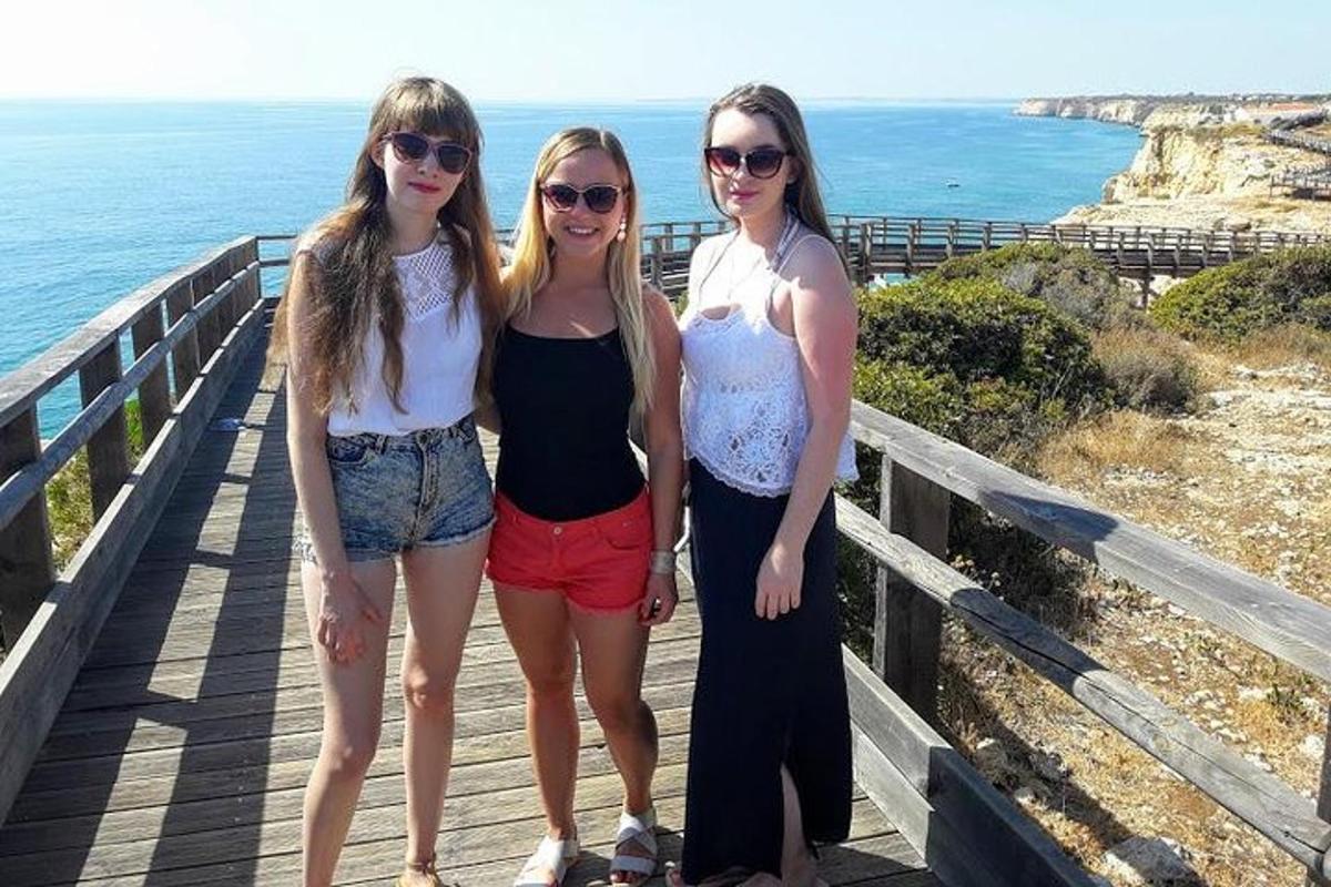 três mulheres em pé em um calçadão perto do oceano