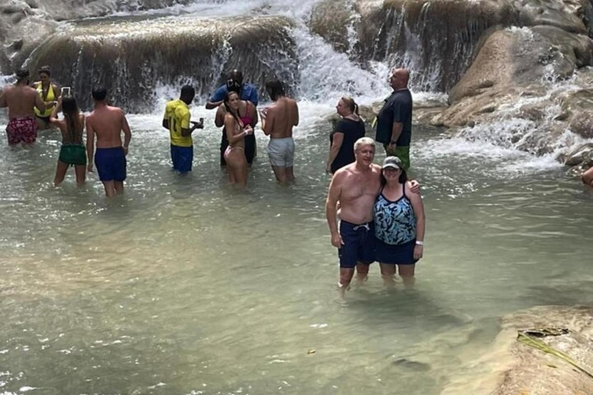 Un grupo de personas de pie en el agua cerca de una cascada.