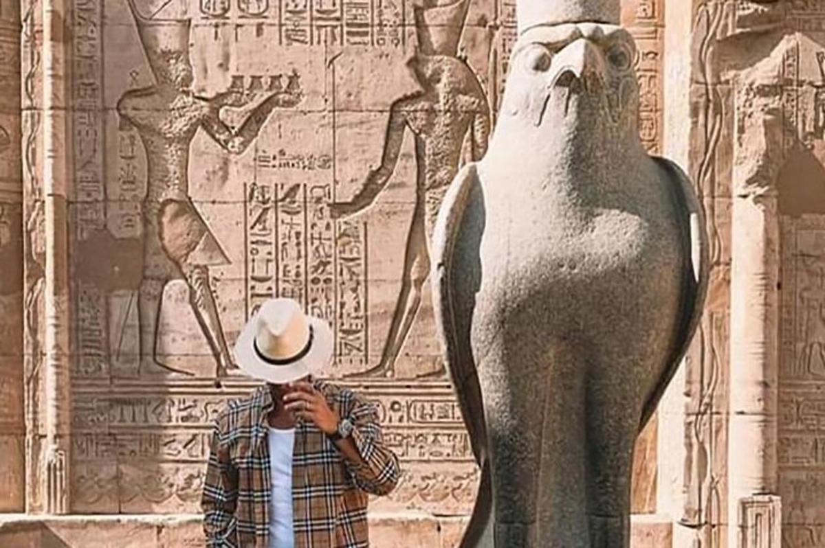 um homem usando um chapéu em pé ao lado de uma estátua