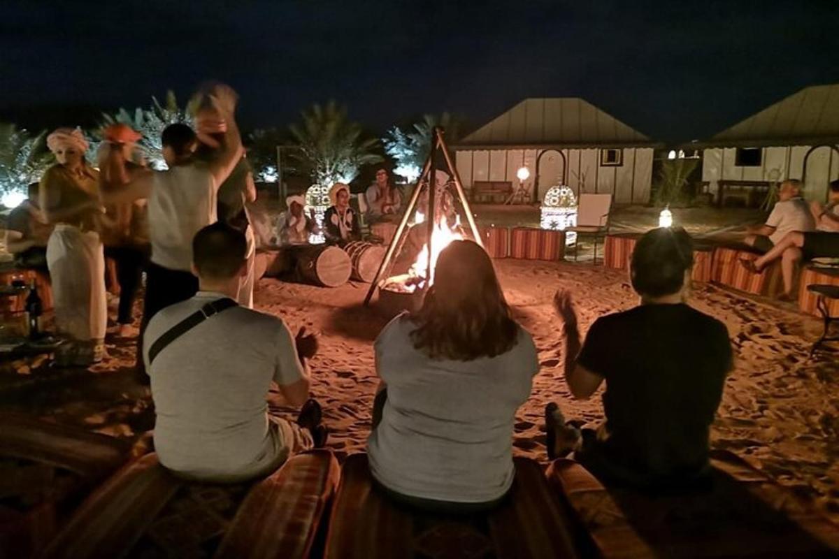 a group of people sitting around a bonfire on the beach