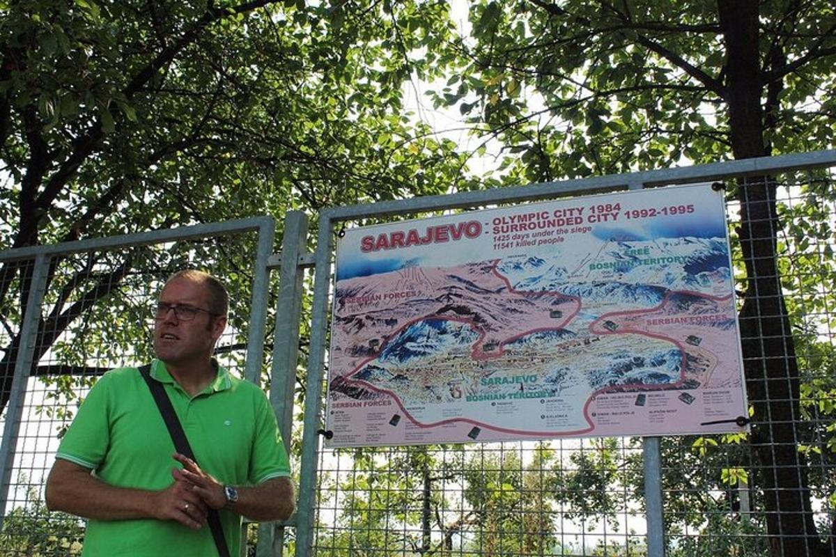 a man standing next to a sign next to a fence