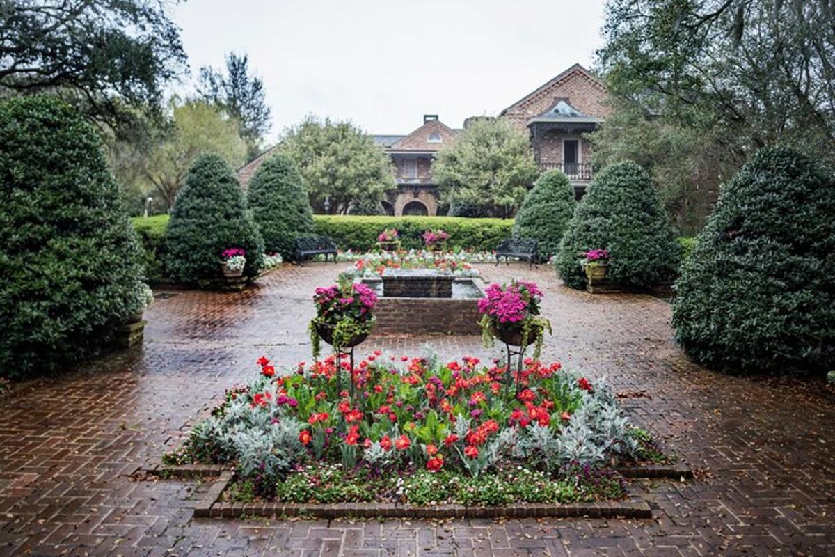 a garden with flowers and a fountain in front of a house