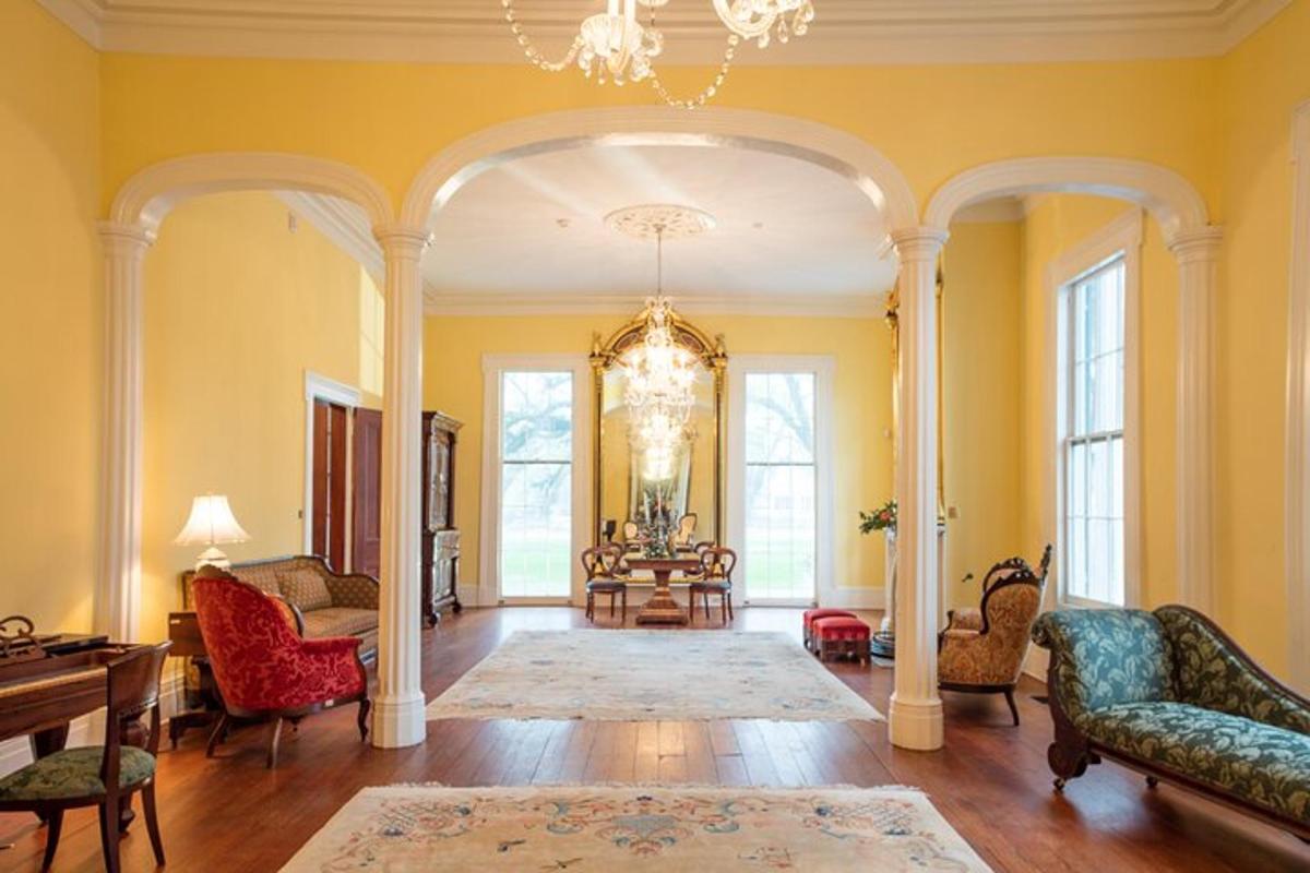 a living room with yellow walls and a chandelier